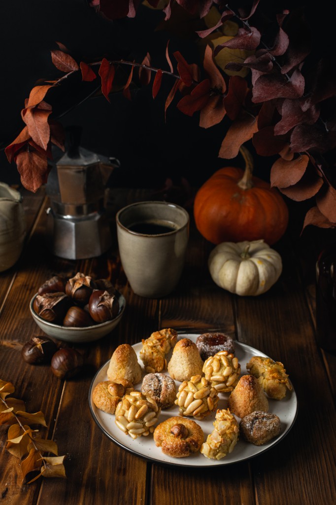 All Saints Day marzipan sweet panellets and roasted chestnuts, autumn leaves on wooden table