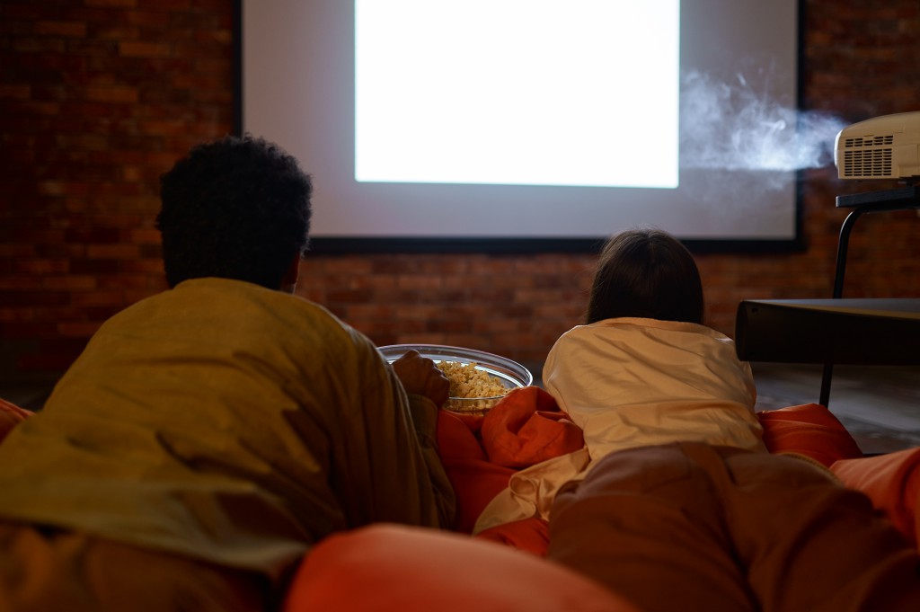 Couple lying on soft bag watching projector