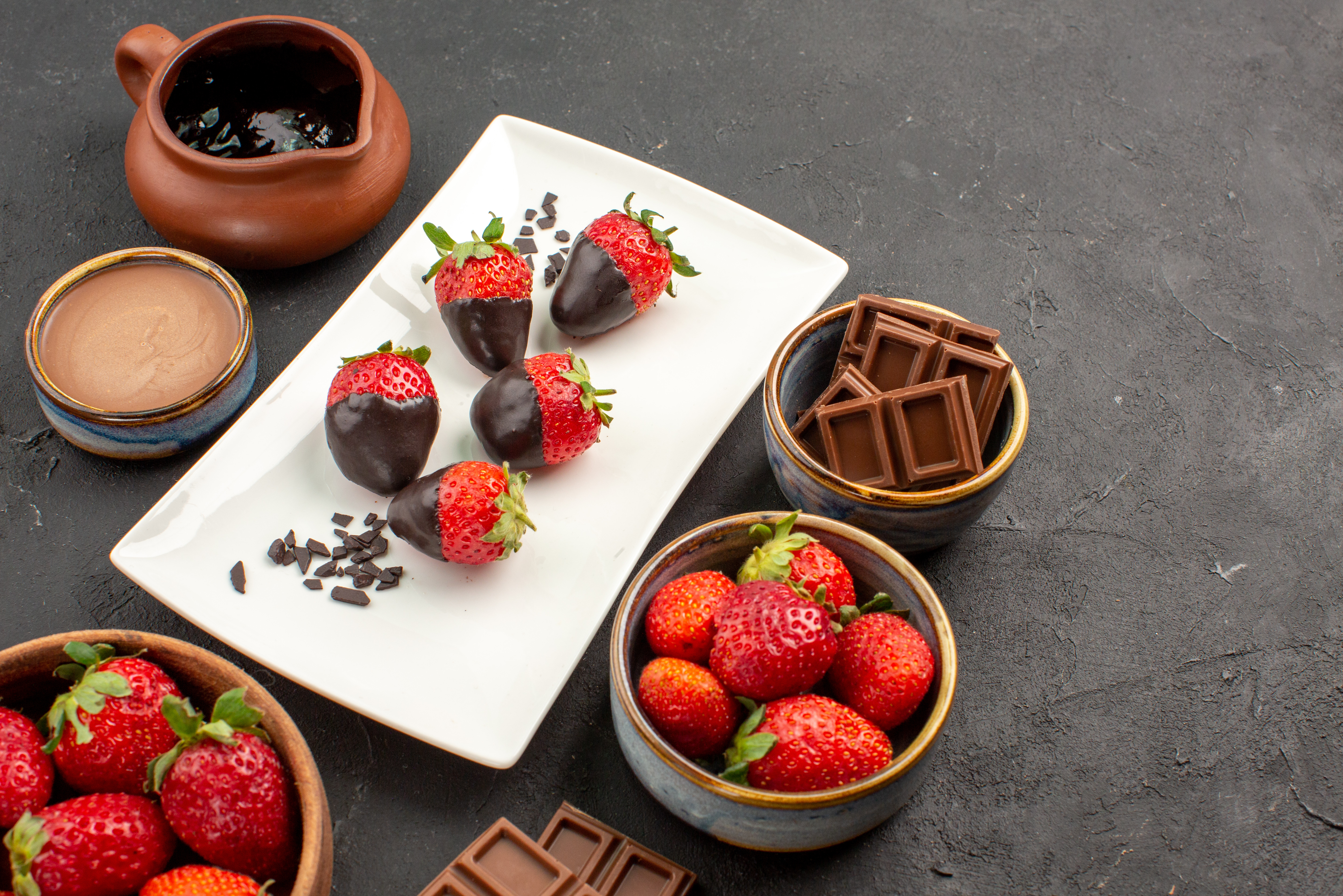 side-close-up-view-chocolate-bowl-red-strawberries-chocolate-cream-bowl-white-plate-chocolate-covered-strawberries-dark-table